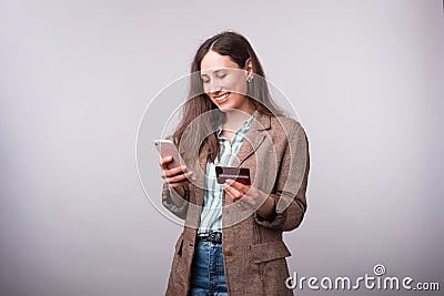 Photo of happy young woman in casual using mobiel phone and holding credit card Stock Photo