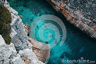 A photo highlighting the rugged beauty of a body of water that is adjacent to rocks, A cinematic shot from above of a turquoise Stock Photo