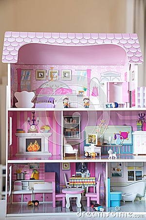 The photo of huge pink dollhouse model furnished with miniature furniture in a kidâ€™s room Stock Photo