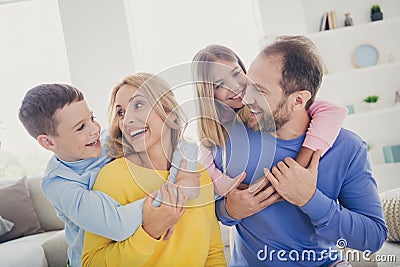 Photo of idyllic mommy daddy hug piggyback two small kids on family weekend holiday in house indoors Stock Photo