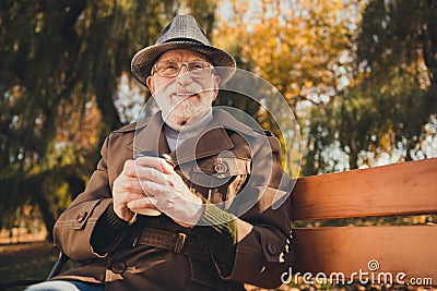 Photo of inspired old man sit bench drink hold takeout coffee mug dream sunny yellow colorful sunshine weather fall park Stock Photo
