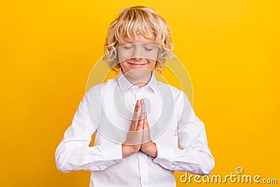 Photo of inspired schoolboy close eyes hold palms plead wear school uniform isolated yellow color background Stock Photo