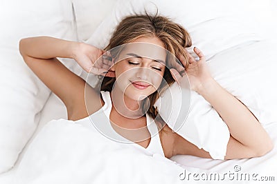 Photo of joyful caucasian woman smiling and while lying in bed Stock Photo