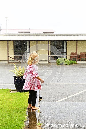 Photo of little girl standing under rain in Greymouth, New Zealand Stock Photo