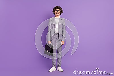 Photo of little schoolkid guy hold case stand posing wear spectacles grey suit isolated purple color background Stock Photo