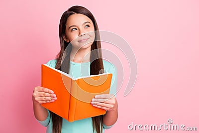 Photo of lovely sweet little ponderous latin lady long hairstyle arms hold orange book sly look up empty space Stock Photo