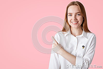 Photo of lovely youngster with long hair, pleasant appearance, indicates aside at blank copy space, shows place for your advertisi Stock Photo