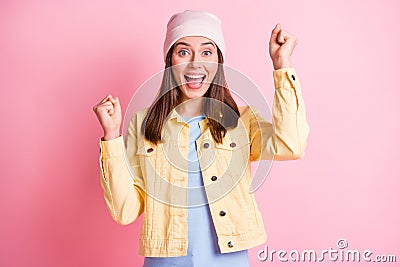 Photo of lucky charming young woman dressed casual clothes cap rising fists open mouth isolated pink color background Stock Photo