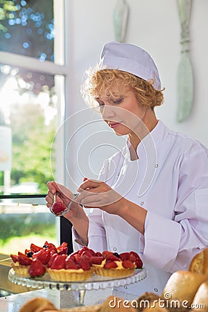 Mature chef arranging fresh strawberry tarts in restaurant Stock Photo