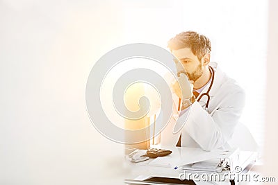 Photo of mature doctor looking at patientâ€™s medical result on his computer in hospital Stock Photo