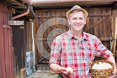 Mature farmer wearing hat while carrying fresh eggs in basket at barn Stock Photo