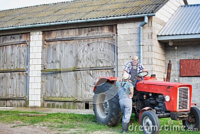 Mature farmer wearing hat and driving tractor Stock Photo