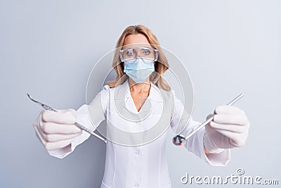 Photo of mature stomatologist woman in face mask doing dental procedure in camera isolated on grey color background Stock Photo