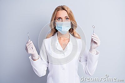 Photo of mature stomatologist woman in face mask and white coat hold dental equipment isolated on grey color background Stock Photo