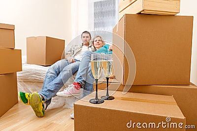 Photo of man and woman sitting on sofa among cardboard boxes with two wine glasses Stock Photo