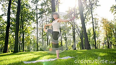 Photo of middle aged smiling woman practising yoga asana. Persong meditating in nature. Balance and harmony of body and Stock Photo