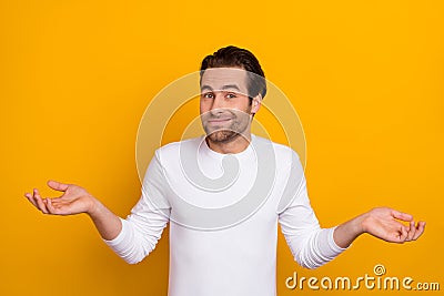 Photo of millennial unsure brunet guy shrug shoulders wear white shirt isolated on bright yellow color background Stock Photo