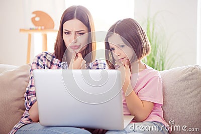 Photo of minded serious older sister siblings look laptop sit sofa puzzled indoors inside house home Stock Photo