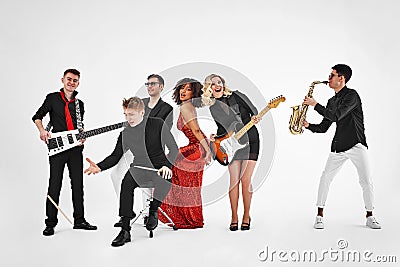 Photo of multi ethnic music band in studio.Musicians and woman soloist posing over white background Stock Photo