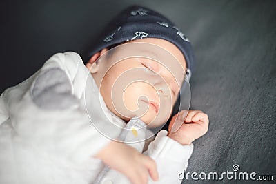 Newborn baby sleeping on gray bedspread on bed. Happy motherhood concept, adoption Stock Photo