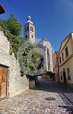 Photo of the old narrow cobblestone (natural stone) streets of medieval European small town, going to an ancient Catholic Church. Stock Photo