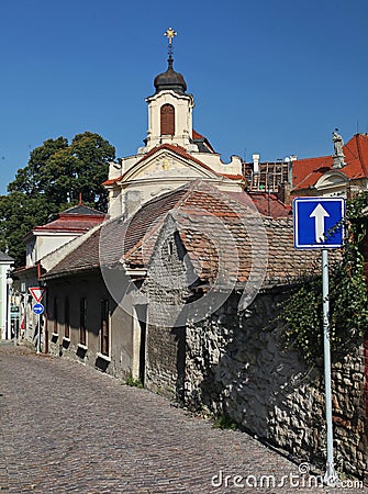 Photo of the old narrow cobblestone (natural stone) streets of medieval European small town, going to an ancient Catholic Church. Stock Photo