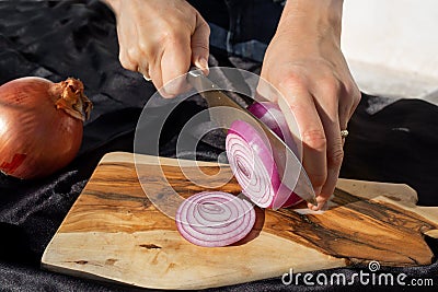 Photo of the onion slicing process. A woman cuts onions into circles with a knife Stock Photo