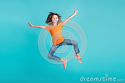 Photo of overjoyed cheerful girl wear trendy orange clothes have fun jump up open hnds hug cudle isolated on cyan color Stock Photo