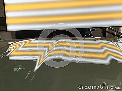 A photo of a paintless dent repair hail light on a hood showing the dents from a hail storm. Stock Photo