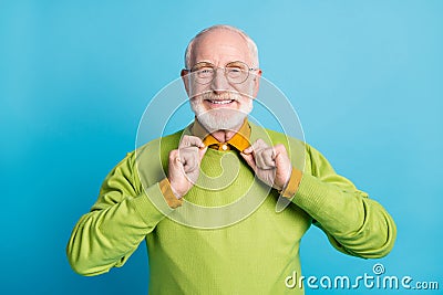 Photo of pensioner grandpa hands hold collar look camera wear specs green sweater isolated blue color background Stock Photo