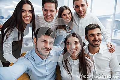Photo from the phone. Young team making selfie in classical clothes in the modern good lighted office Stock Photo