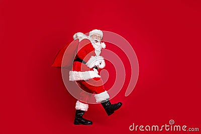 Photo portrait of amazed santa claus with open mouth carrying huge bag of gifts isolated on bright red colored Stock Photo