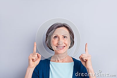 Photo portrait of elder woman curious pointing fingers up copyspace isolated on grey color background Stock Photo