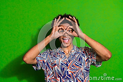 Photo portrait of funny joking happy student man comic showing okey sign his eyes looks like goggles isolated over green Stock Photo