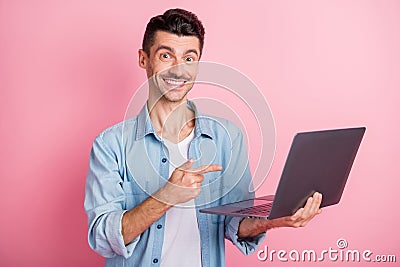 Photo portrait geek pointing finger computer smiling recommending in blue shirt isolated pastel pink color background Stock Photo