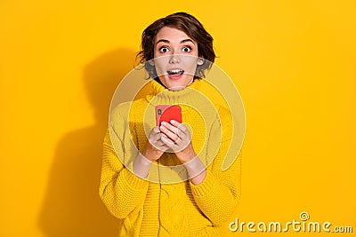 Photo portrait of girl bob hairstyle amazed shocked reading information with cellphone staring isolated on vivid yellow Stock Photo
