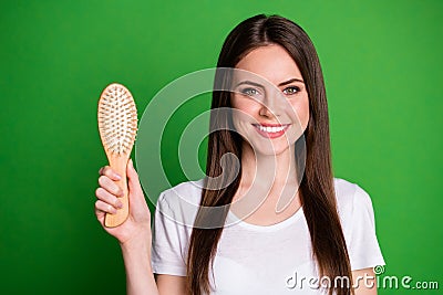 Photo portrait of girl holding hairbrush isolated on vivid green colored background Stock Photo