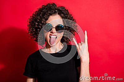 Photo portrait of girl showing rock goat sign with tongue out isolated on vivid red colored background Stock Photo