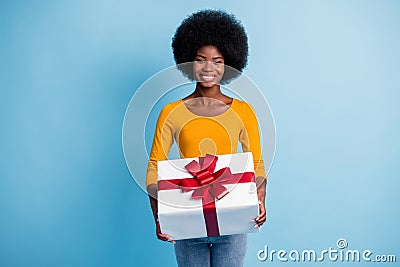 Photo portrait of happy smiling black skinned woman holding wrapped with red ribbon gift isolated on vibrant blue color Stock Photo