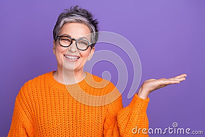 Photo portrait of marketing promoter advertiser pensioner woman holding arm empty space presentation isolated on violet Stock Photo