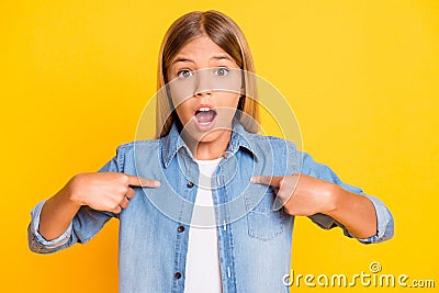Photo portrait of sad upset schoolgirl pointing on herself asking surprised wearing denim shirt isolated on bright Stock Photo