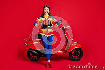 Photo portrait of screaming girl holding helmet in two hnads sitting on scooter isolated on vivid red colored background Stock Photo