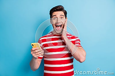 Photo portrait of student shocked surprised keeping mobile phone blogging isolated on bright blue color background Stock Photo