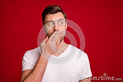 Photo portrait of surprised guy keeping secret closed mouth with hand staring blank space isolated bright red color Stock Photo