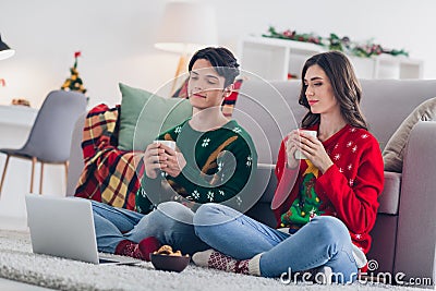 Photo portrait of two young interested concentrated people wear cozy cute ugly sweaters drink hot cappuccino watch Stock Photo