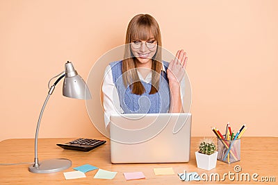 Photo portrait of woman smiling waving hand greeting video call laptop at desk wearing blue vest isolated on pastel Stock Photo