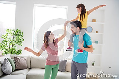 Photo of positive cheerful three people mommy daddy carry shoulders little kid girl hold hand in house indoors Stock Photo