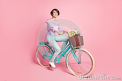 Photo of positive lady drive bike deliver flowers wear violet blouse pants shoes isolated pink color background Stock Photo