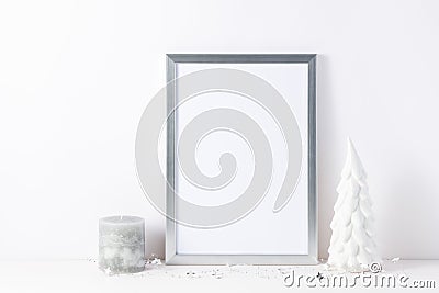 Photo or poster mockup with a silver frame, small decorative ceramic christmas tree and candle on white Stock Photo