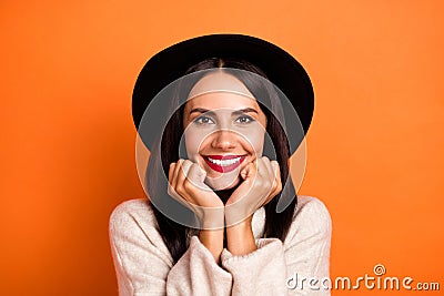 Photo of pretty adorable young woman wear beige sweater headwear arms cheeks chin isolated orange color background Stock Photo